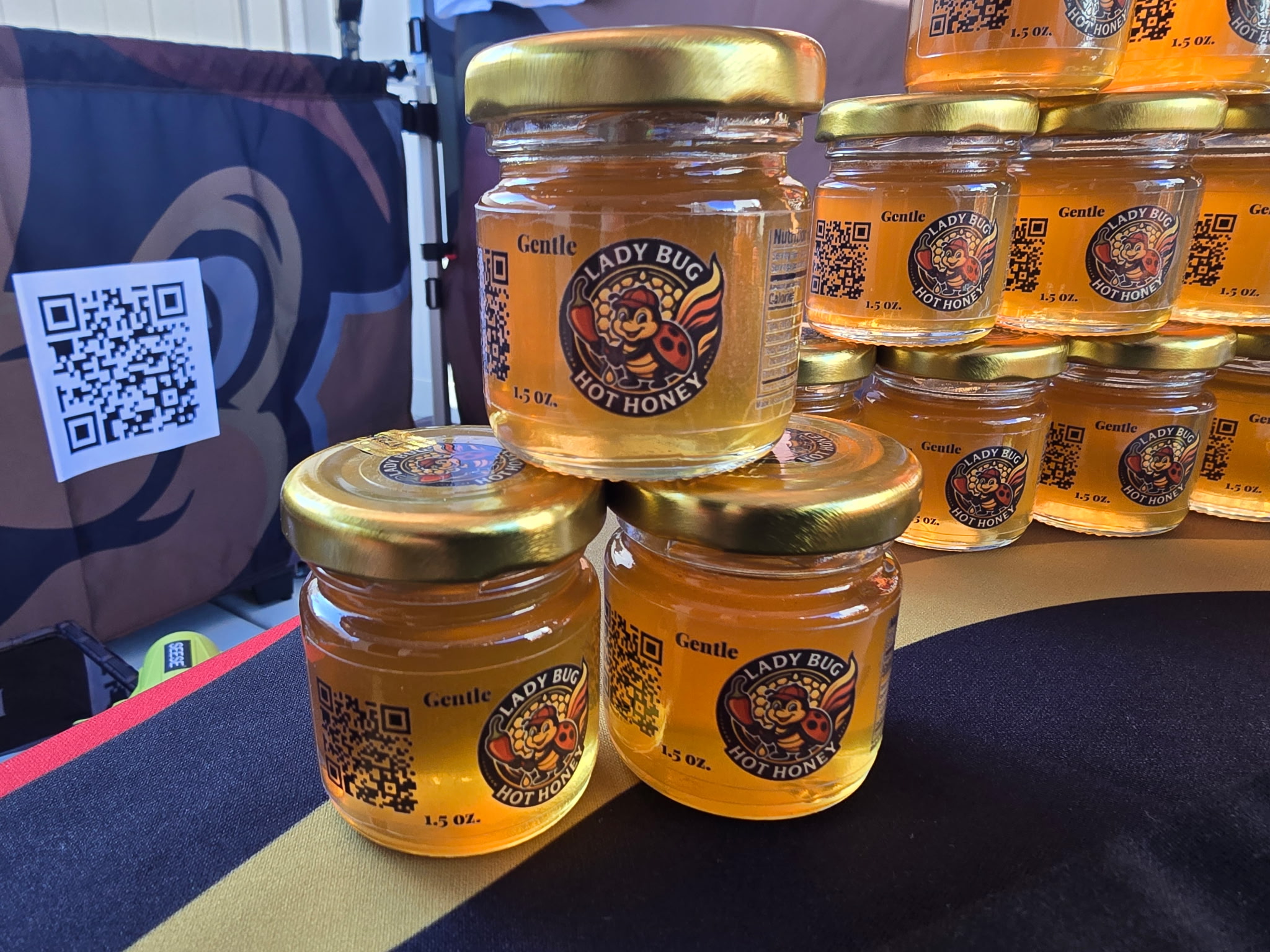LadyBug Hot Honey booth at a Sacramento farmers market with banner and bottles